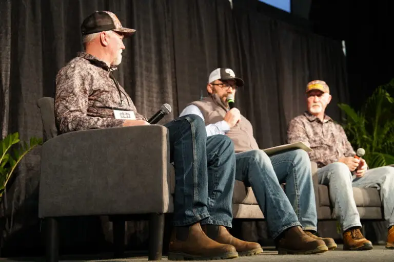 Three speakers on stage presenting at a seminar during the Midwest Sportsmen Classic in Shipshewana, Indiana.