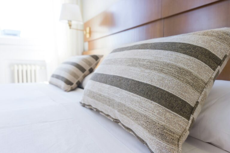 Comfortable hotel bed with striped pillows, representing quality accommodations for visitors in Shipshewana, Indiana.